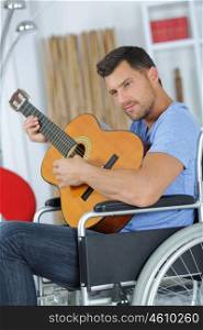 Man in wheelchair playing acoustic guitar