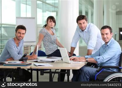 Man in wheelchair sat at desk with colleagues