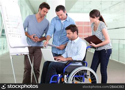 Man in wheelchair surrounded by colleagues