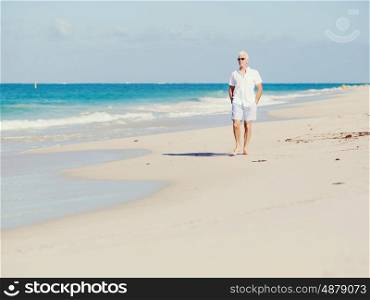 Man in white clothes on the beach on sunny day. Beautiful day on the beach