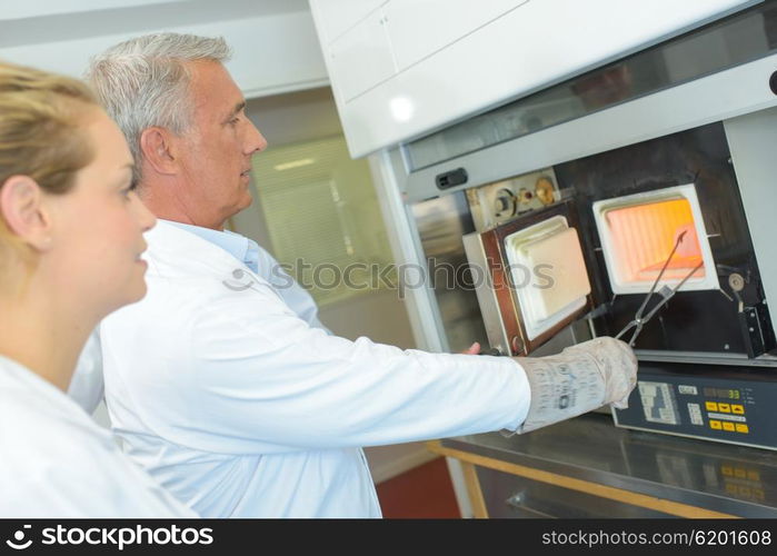 Man in white coat removing item from oven