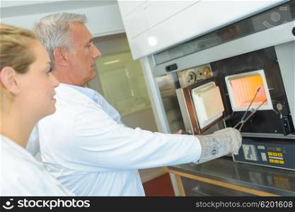 Man in white coat removing item from oven