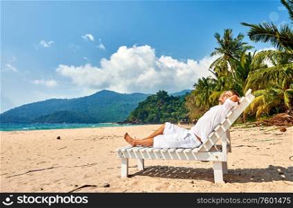 Man in white relaxing in sun bed on a tropical beach at Tioman Island, Malaysia