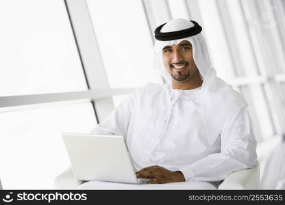 Man indoors with laptop smiling (high key/selective focus)