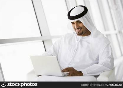 Man indoors with laptop smiling (high key/selective focus)