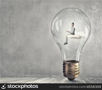 Man inside bulb. Young businessman inside of light bulb reading book