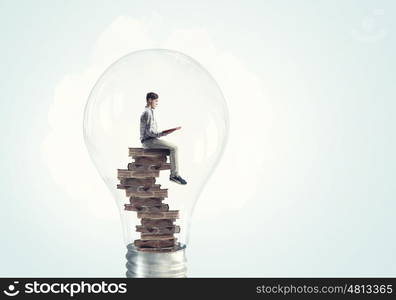 Man inside bulb. Young businessman inside of light bulb reading book