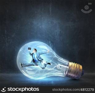 Man inside of electric bulb. Jumping businessman inside glass light bulb as brainstorming concept
