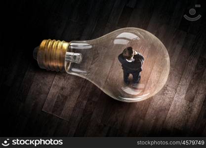 Man inside of electric bulb. Thoughtful businessman inside glass light bulb as brainstorming concept
