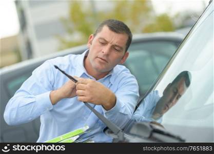 man inspecting the cars wipers