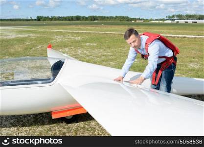 Man inspecting wing of glider