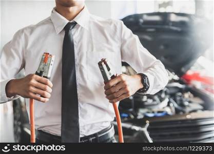 Man inspection holding jumper cables for charger Battery service maintenance of industrial to engine repair.In Factory transport automobile automotive image
