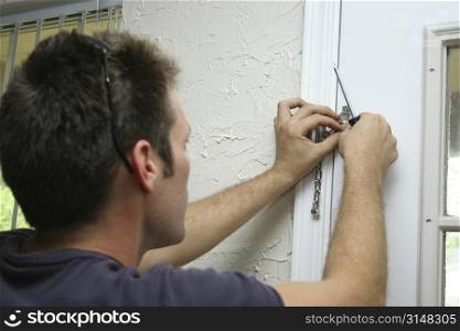 Man installing door chain. Focus on hands.