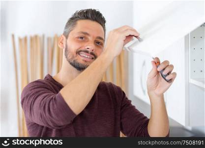 man installing kitchen cupboard