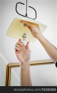 Man installing or changing a bulb, fixing it to the socket at home