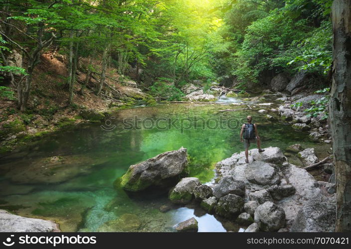 Man into canyon. Spring lake and green forest. Nature composition.