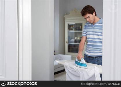 Man ironing shirt in living room