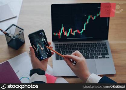 Man is analyzing business data on phone and laptop screens. Sells through internet, information review. Financial graph on laptop screen. Wireless technology, exchange trading. Hard work concept.. Man is analyzing business data on phone and laptop screens. Exchange trading. Hard work concept.