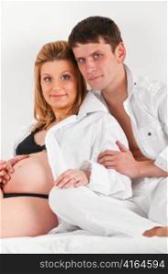 man is embracing his pregnant wife in bed at morning