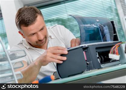 man is fixing a printer