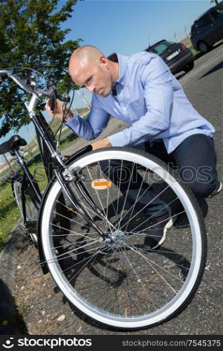man is fixing the bike outdoors