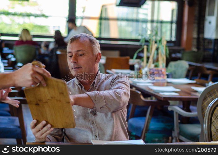 Man is giving order to male waiter in luxury restaurant indoor.