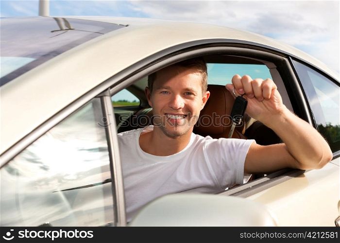 Man is holding his car key sitting himself in the automobile and obviously has fun