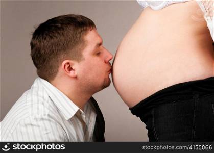 man is kissing stomach of his pregnant wife