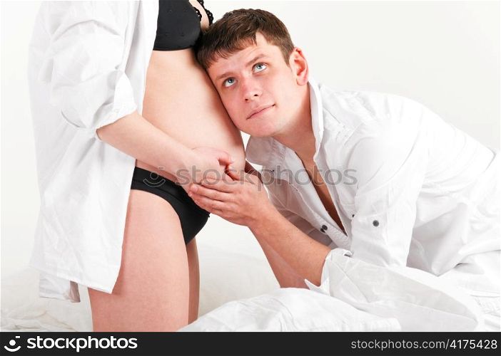 man is listening to baby in stomach of his pregnant wife