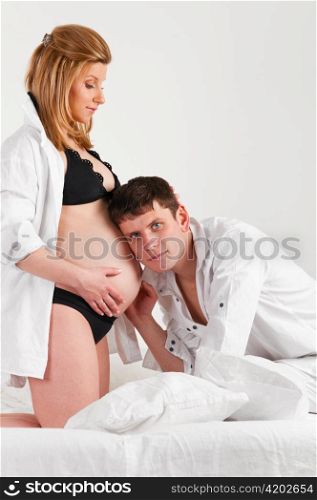 man is listening to baby in stomach of his pregnant wife