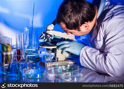 Man is looking into the glass of microscope, doing reseach