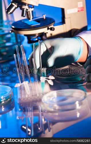 Man is looking into the ocular of microscope, doing reseach