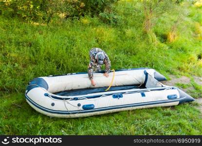 Man is preparing for fishing, inflatable rubber boat pump.
