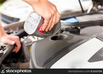 Man is refilling oil in his car, only hands to be seen