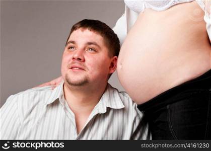 man is trying to listen his baby inside of his pregnant wife