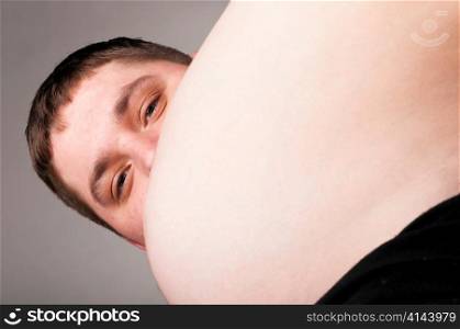 man is watching from behind of the stomach of his pregnant wife