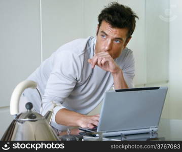 man is working on laptop computer in kitchen