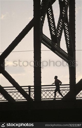 Man Jogging Across a Bridge