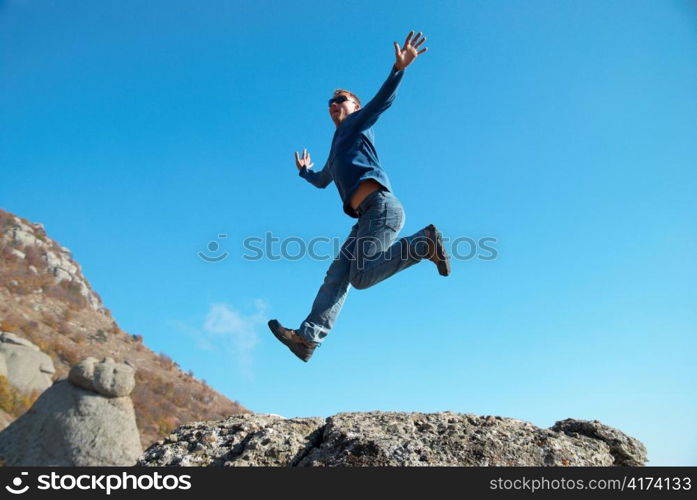 Man jumping on the rocks with landscape background