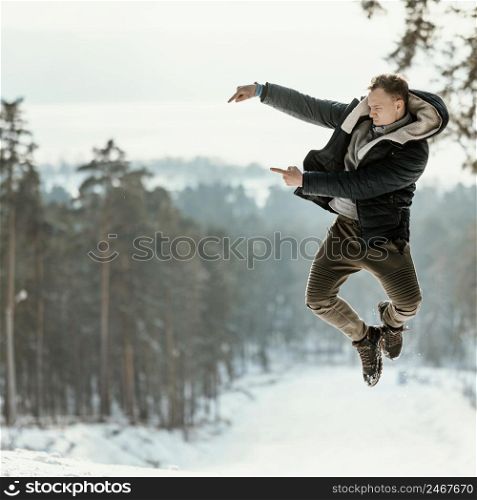 man jumping outdoors nature during winter pointing copy space
