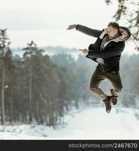 man jumping outdoors nature during winter pointing copy space