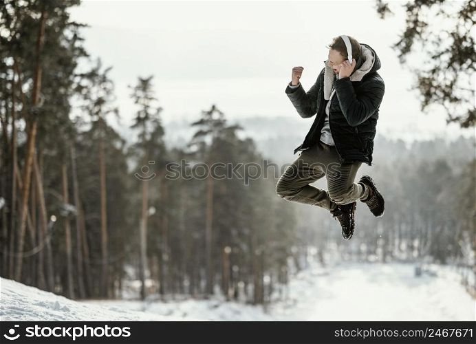 man jumping outdoors nature during winter with copy space