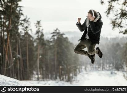 man jumping outdoors nature during winter with copy space