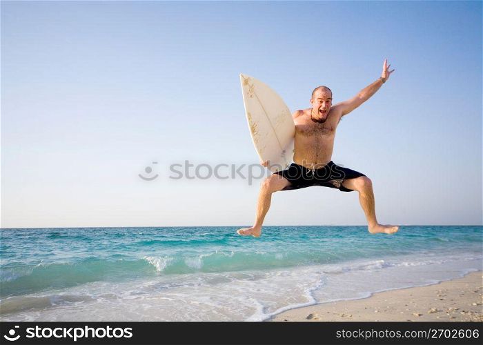 Man jumping with surfboard on beach