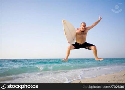 Man jumping with surfboard on beach