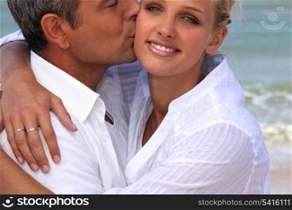 man kissing his blonde girlfriend at beach