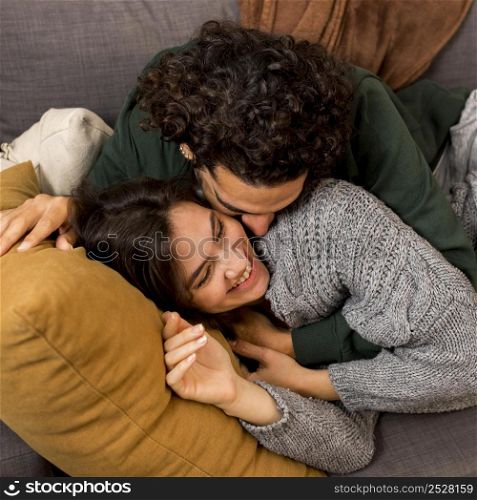 man kissing his wife while lying sofa