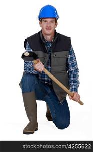Man kneeling with sledge-hammer and wellington boots
