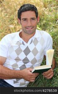 Man laid in field with book in hand