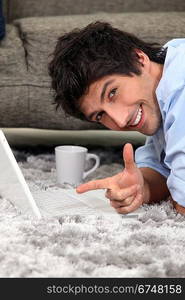 Man laid on a carpet with laptop